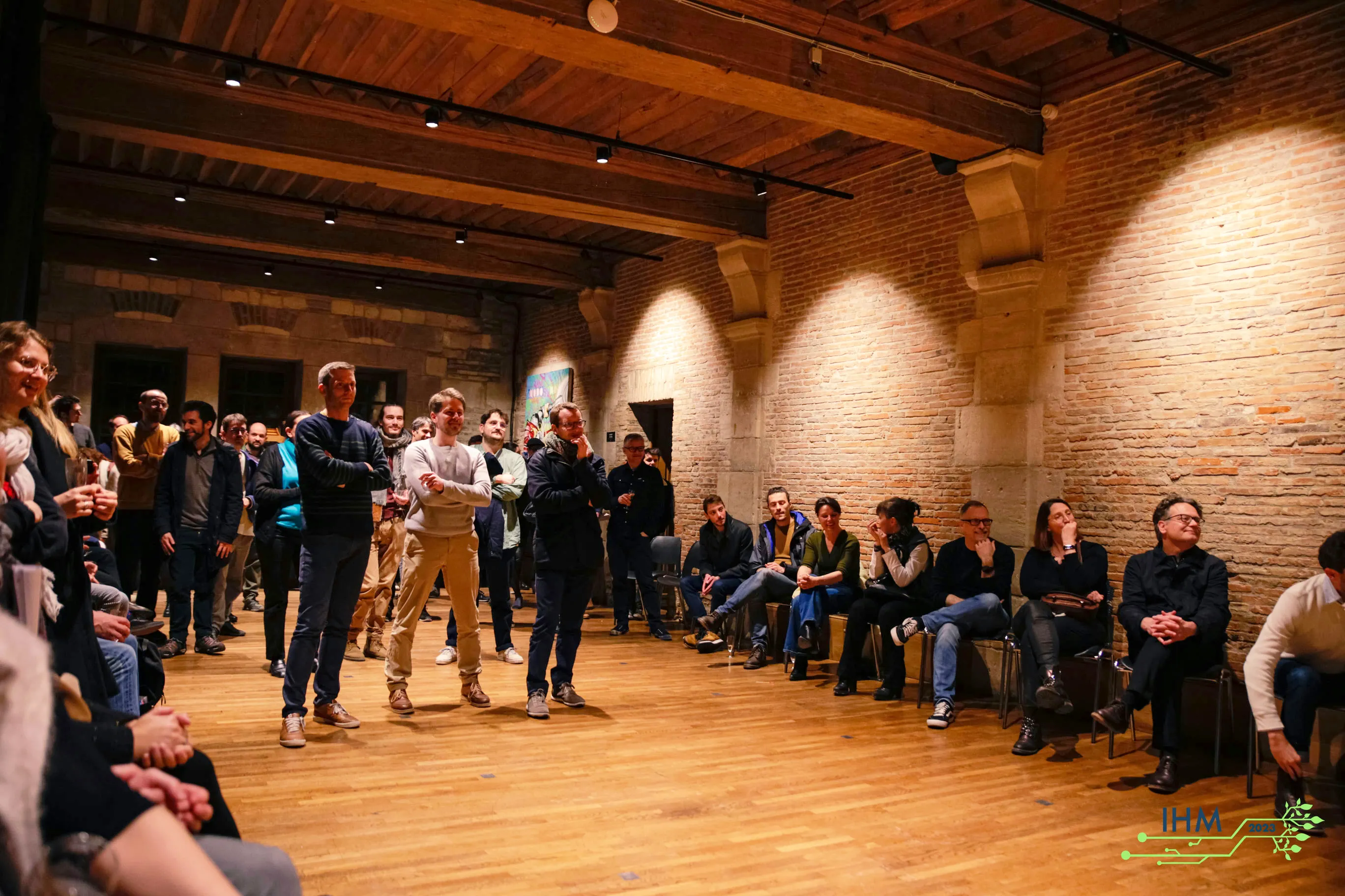 Participants à IHM 2023 dans une salle aux murs de briques